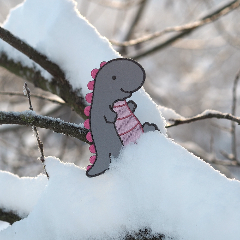 Heijastava brodeerattu dinosaurus haalarimerkki, pinkit yksityiskohdat. Luminen tausta.