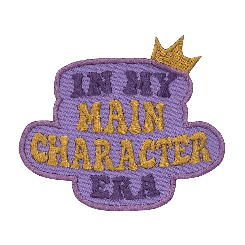 Brodeerattu haalarmerkki, kruunu, teksti: In  my main character era.