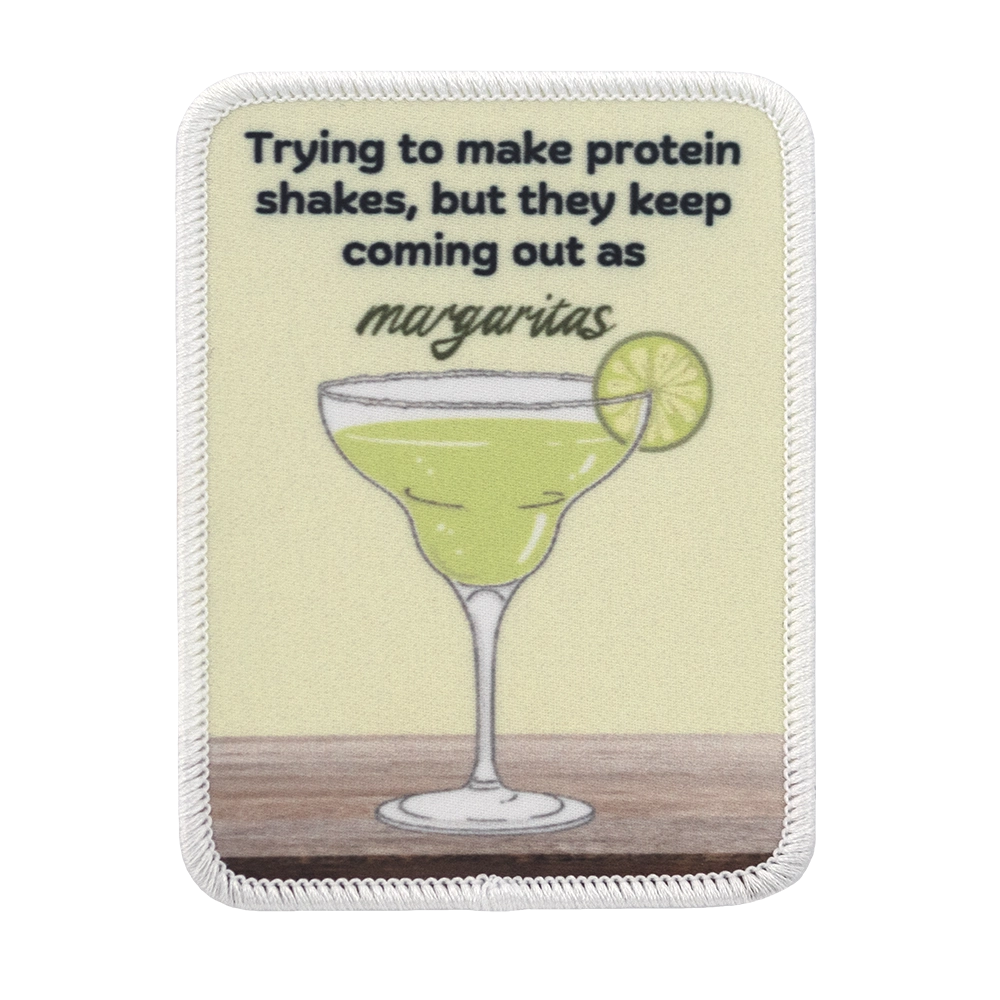 Painettu margarita-aiheinen haalarimerkki, teksti: Trying to make protein shakes, but they keep coming out as margaritas.