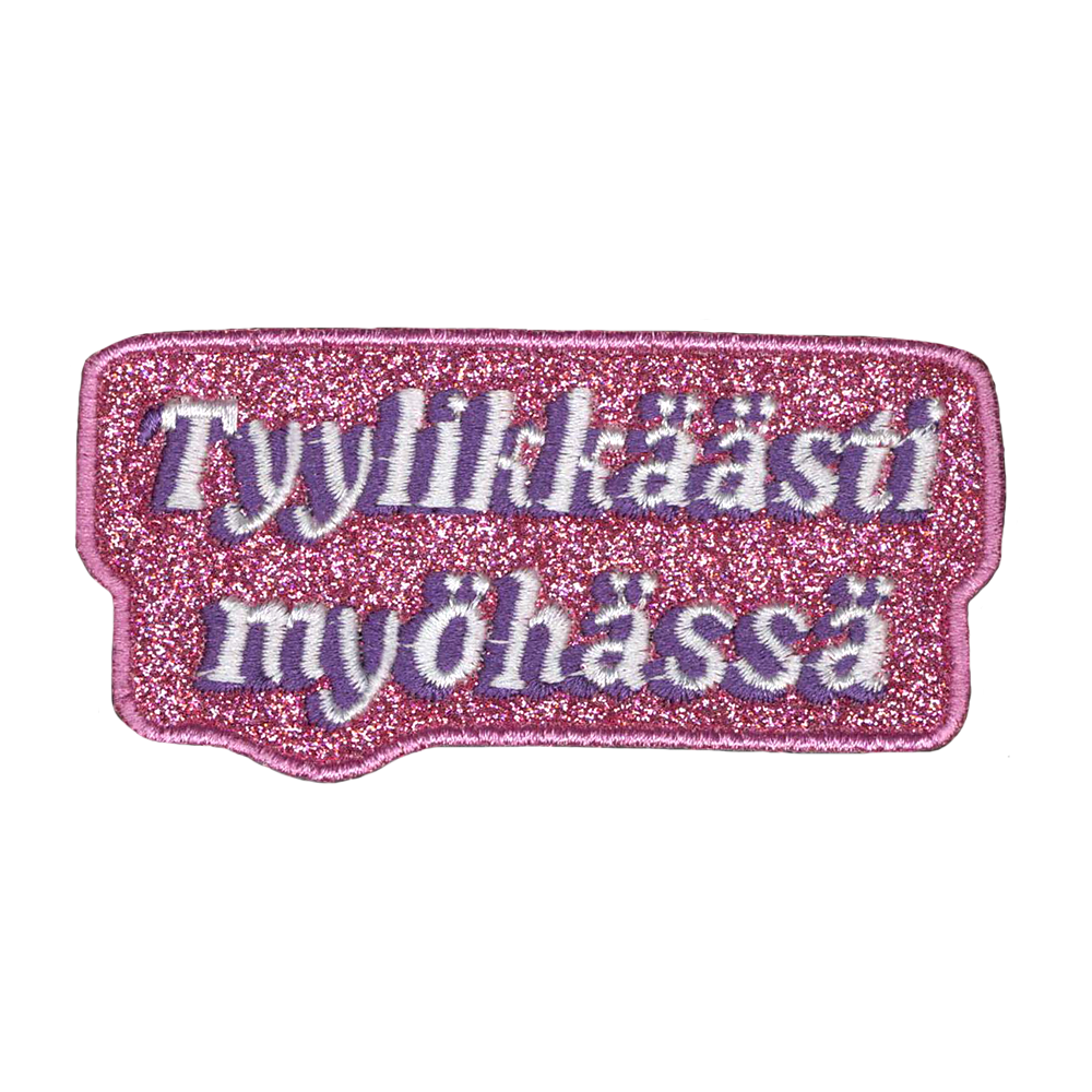 Brodeerattu pinkki kangasmerkki, teksti: Tyylikkäästi myöhässä.