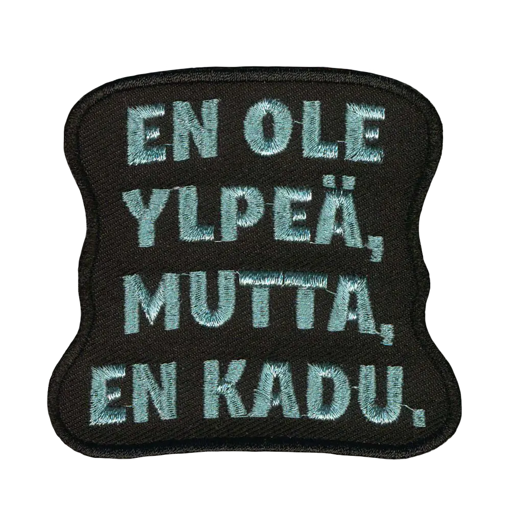 Brodeerattu kangasmerkki, teksti: En ole ylpeä, mutta en kadu.